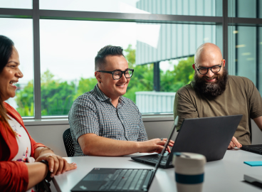Team sitting around a laptop in an office