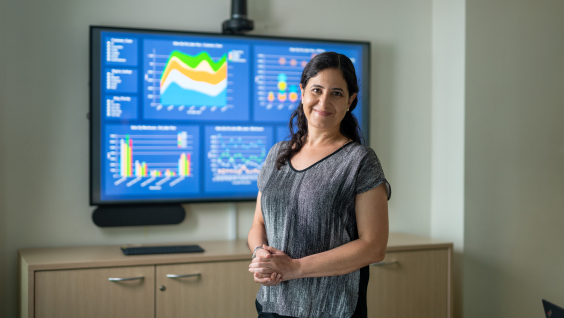 Women standing infront of monitor with analytics
