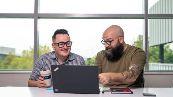 Two men infront of a laptop in an office